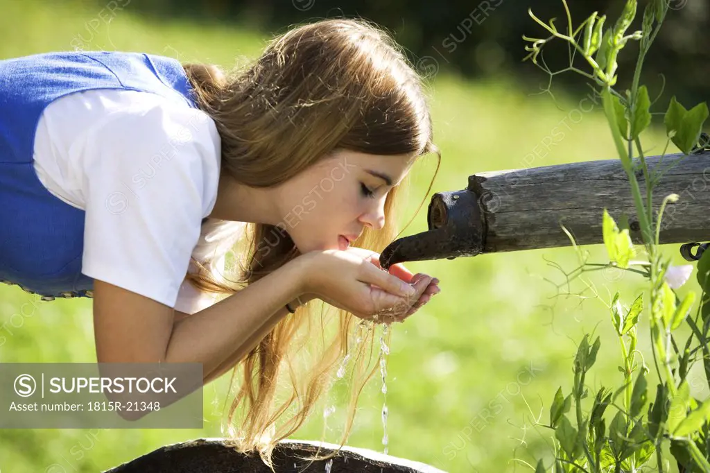 Young woman drinking water from fountain