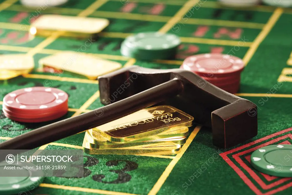 Gambling chips and gold bars on roulette table