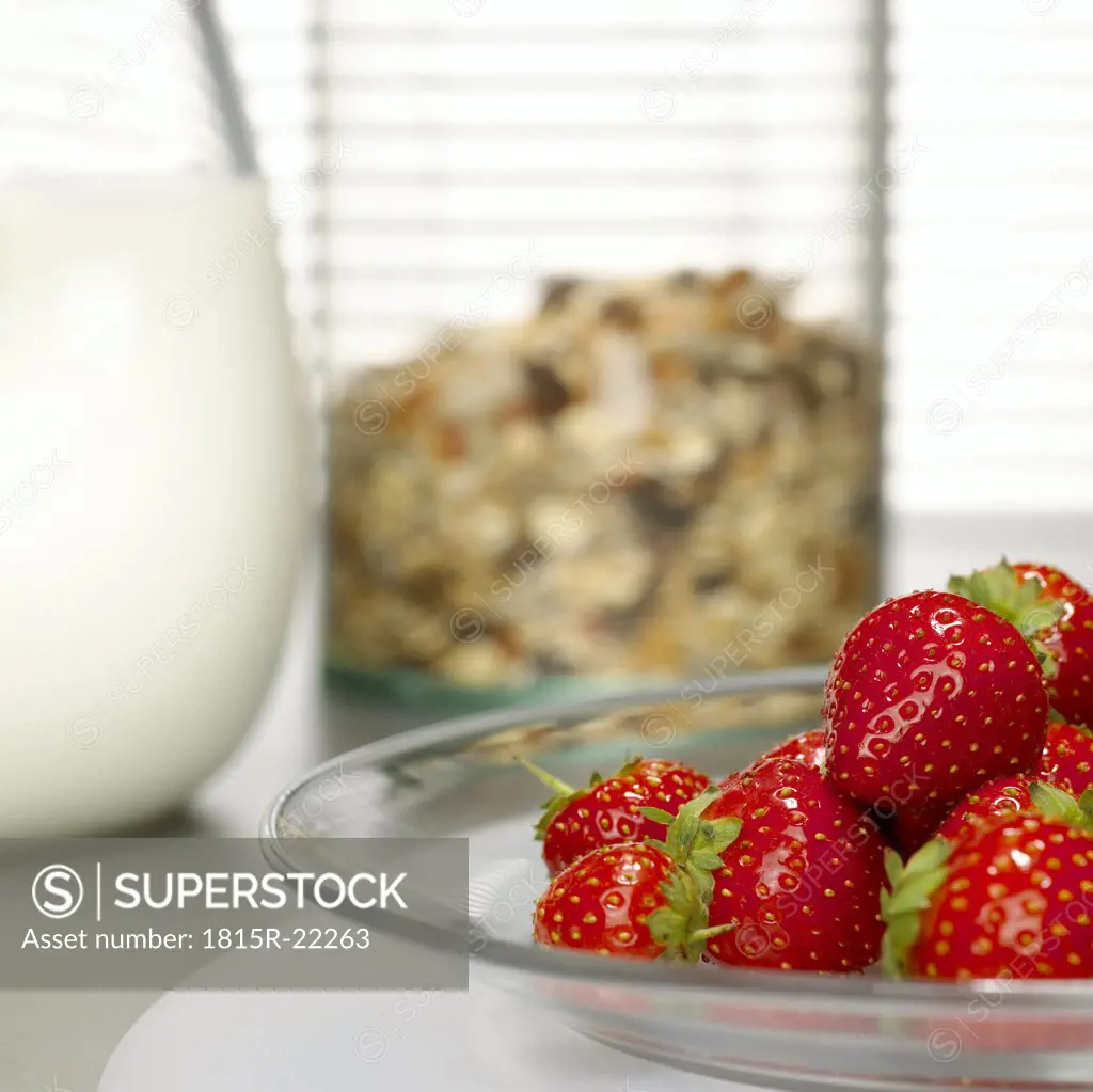 Strawberries on plate, cereals and milk in background