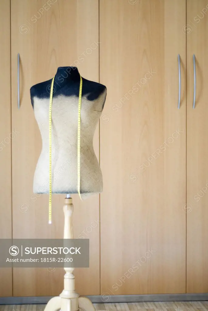 Mannequin and tape measure in front of wardrobe