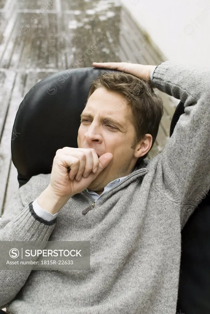 Man in an armchair yawning