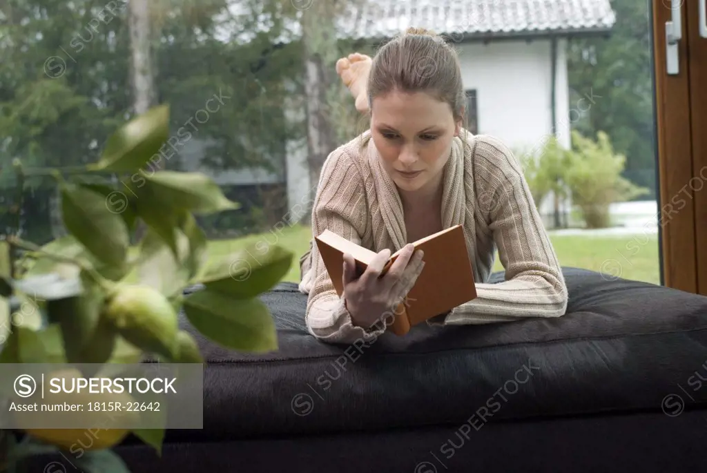Young woman relaxing on sofa reading a book