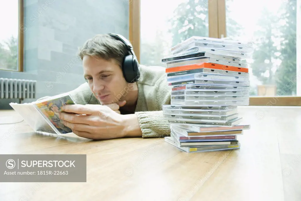 Man with headphones and CDs lying on floor