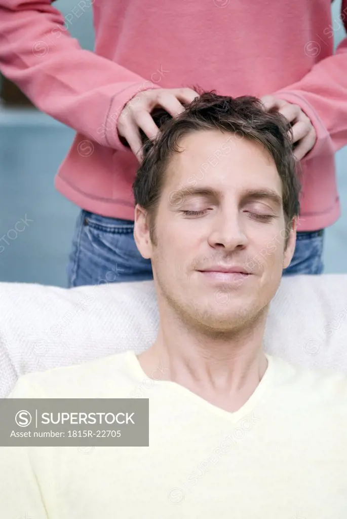Young woman massaging head of her boyfriend