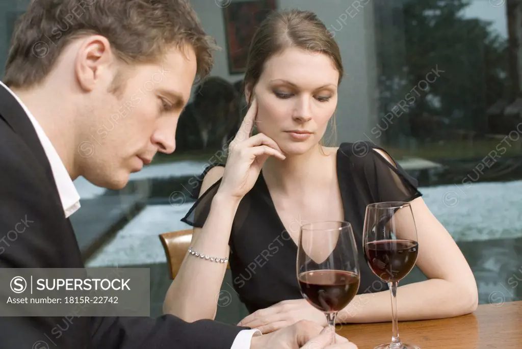 Couple drinking red wine looking unhappy