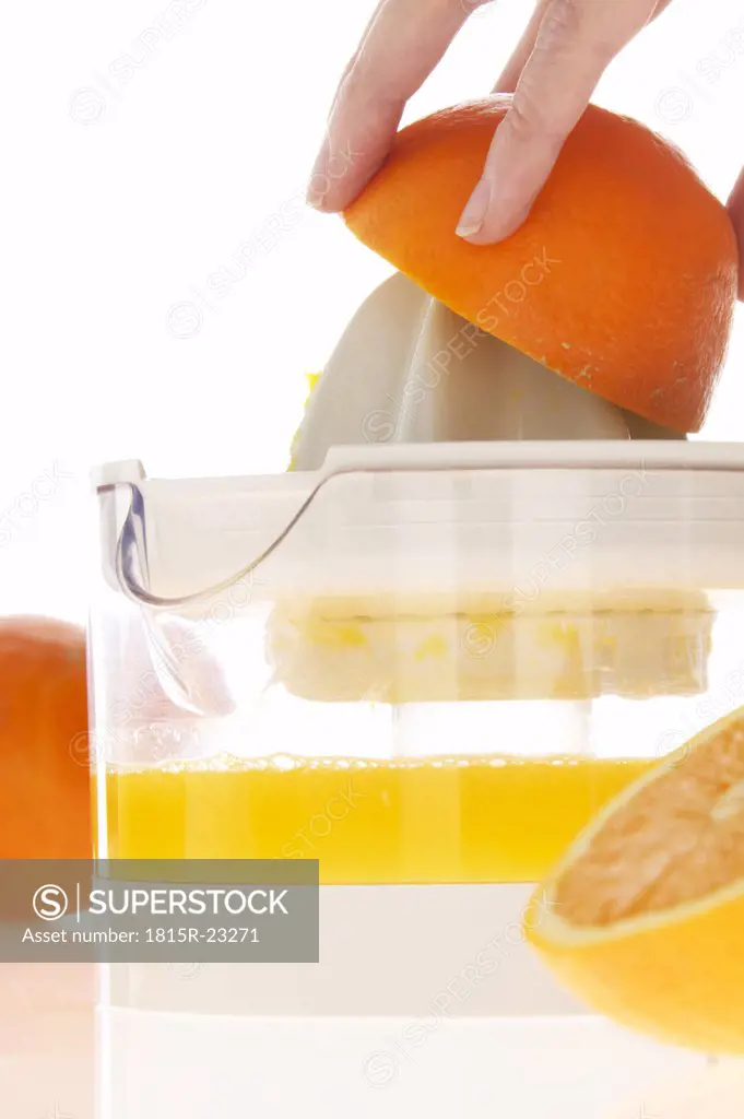 Woman preparing orange juice on juicer, close-up