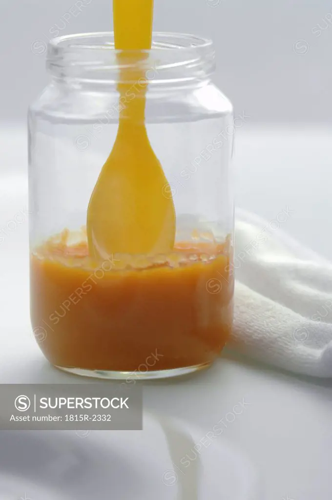 Baby food in jar with spoon, close-up