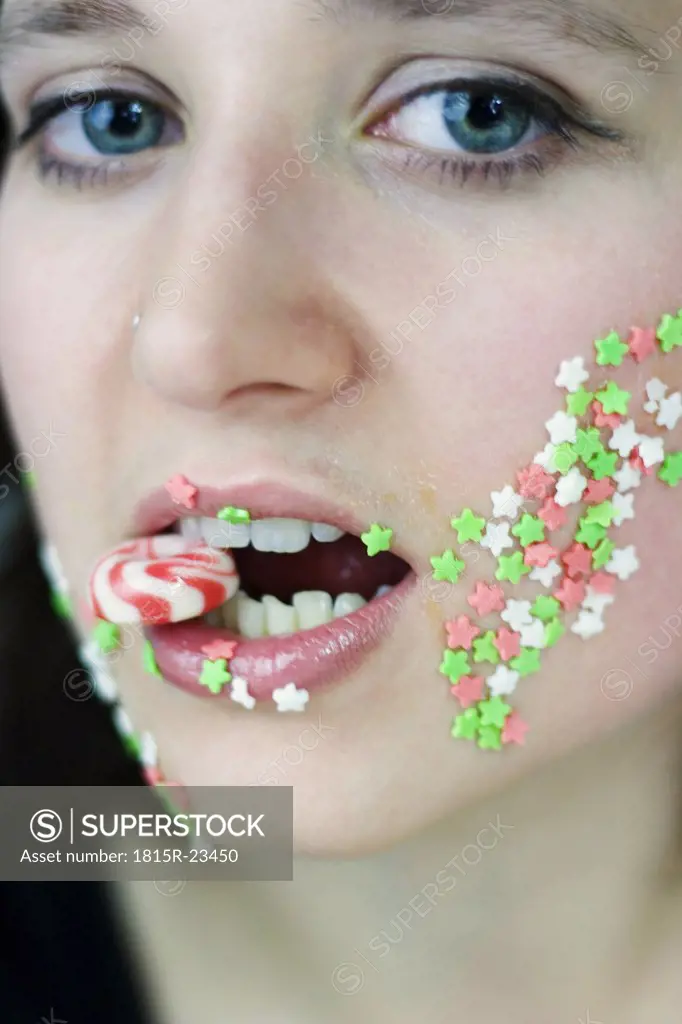 Young woman holding sweet between teeth