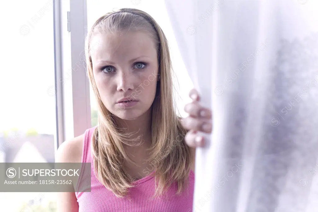 Young woman looking out of window, close-up, portrait