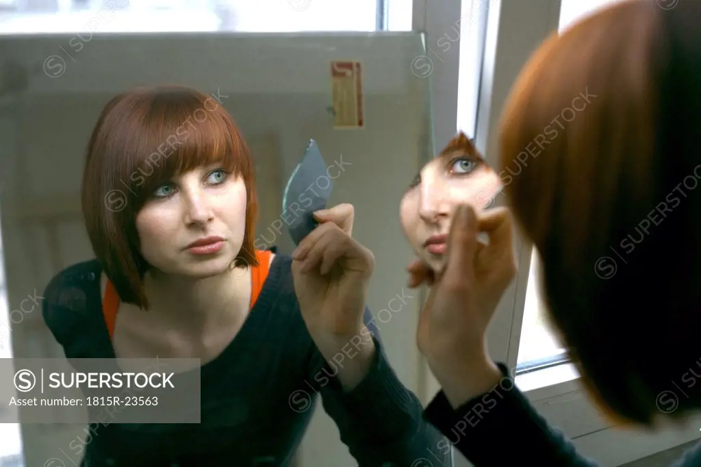Woman looking into mirror, portrait