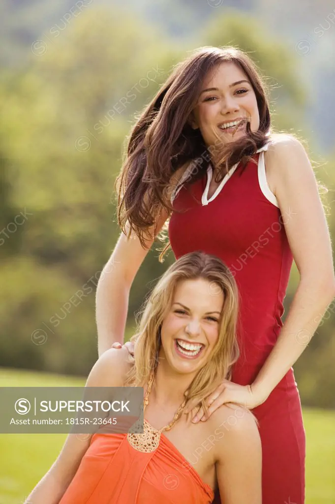 Two young women in meadow, laughing, portrait
