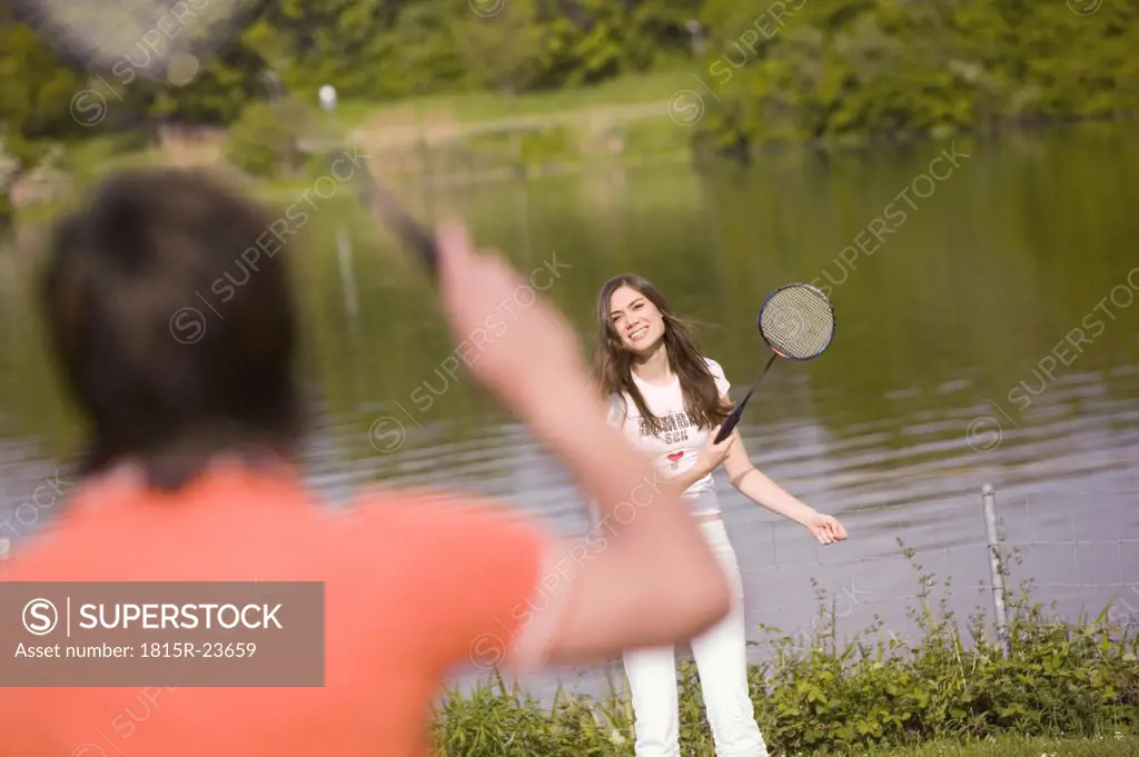 Young couple playing badminton, focus on woman