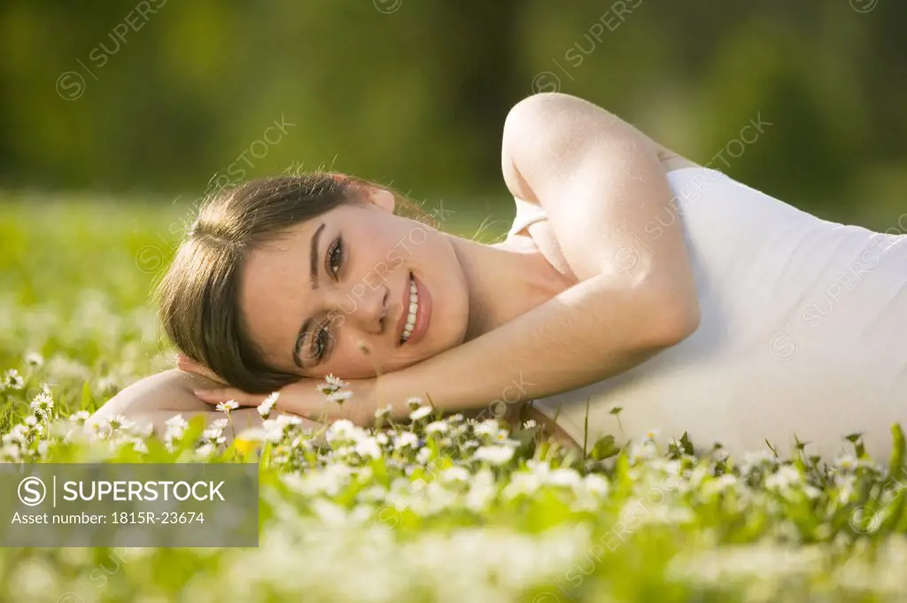 Germany, Bavaria, Munich, young woman lying in meadow