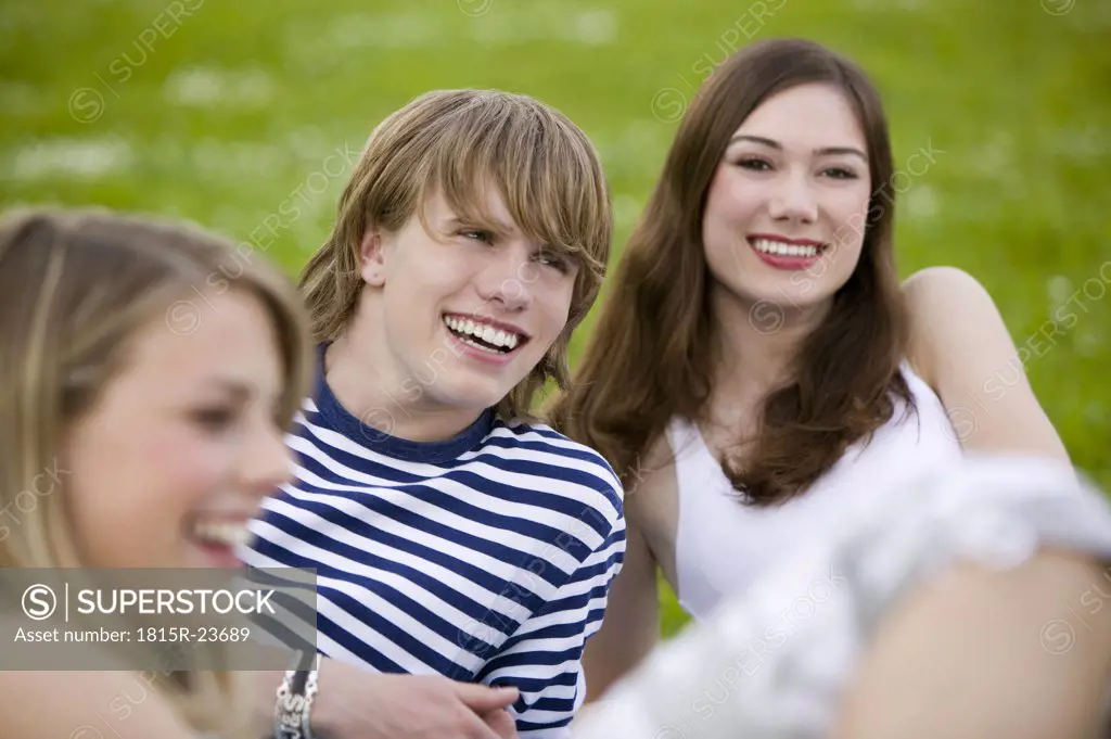 Young people sitting in meadow, smiling