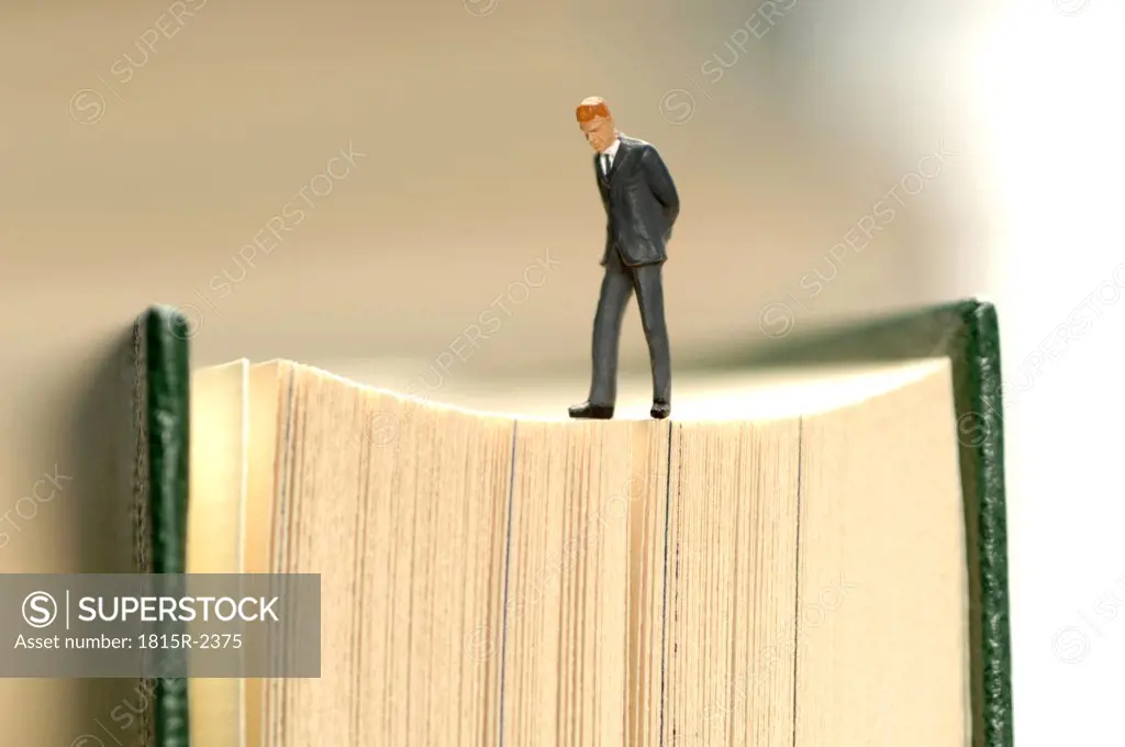 Figurine of businessman kept on book, close-up