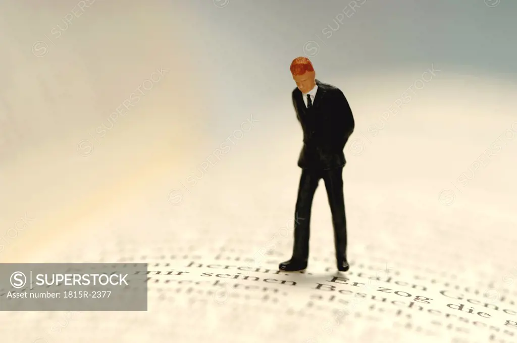 Figurine of businessman kept on open book, close-up
