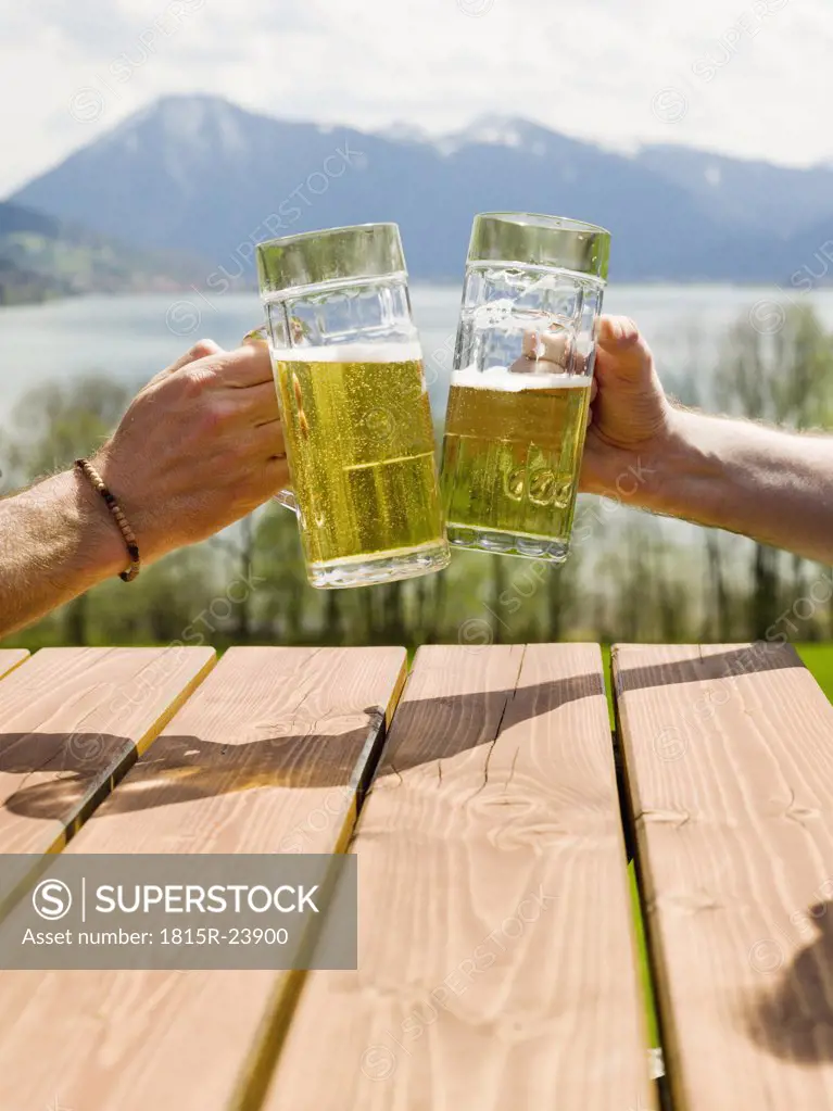 Germany, Bavarian, Tegernsee, two men toasting with beer glasses, close-up