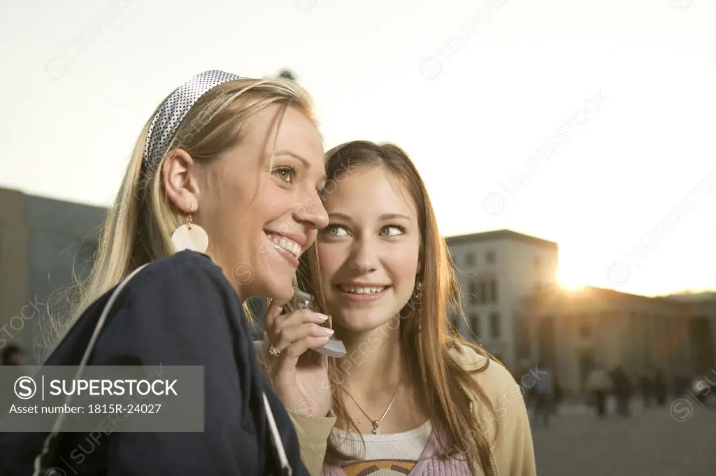 Young women in street, using mobile phone