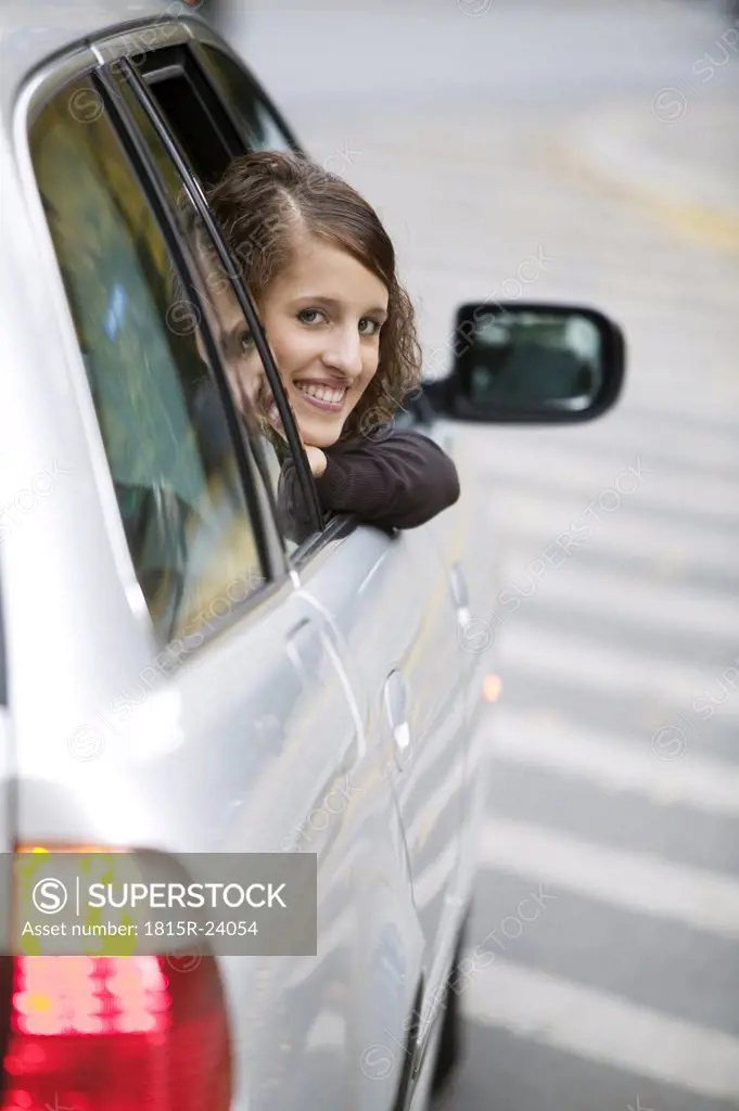 Young woman looking out of car, smiling