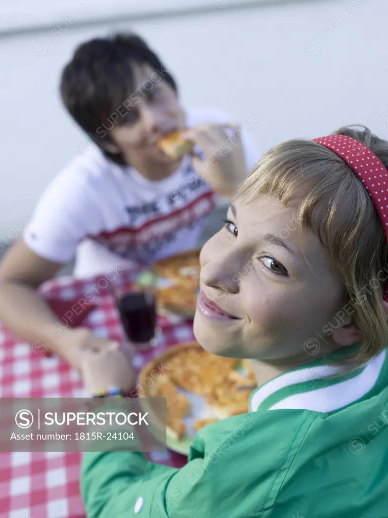 Young couple eating pizza, outdoors