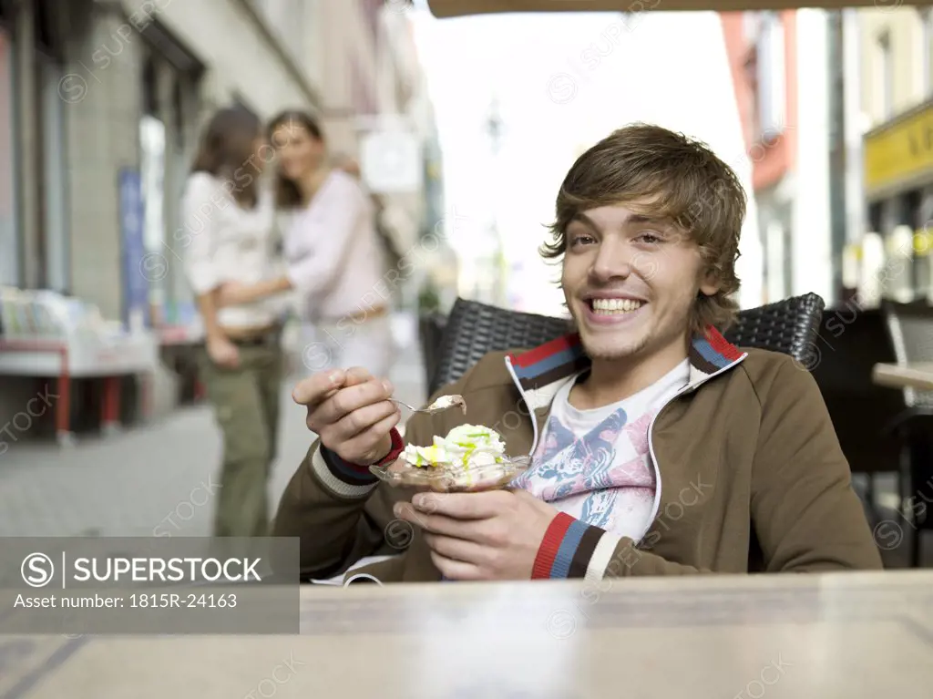 Young man in ice cream parlour, girls watching in background