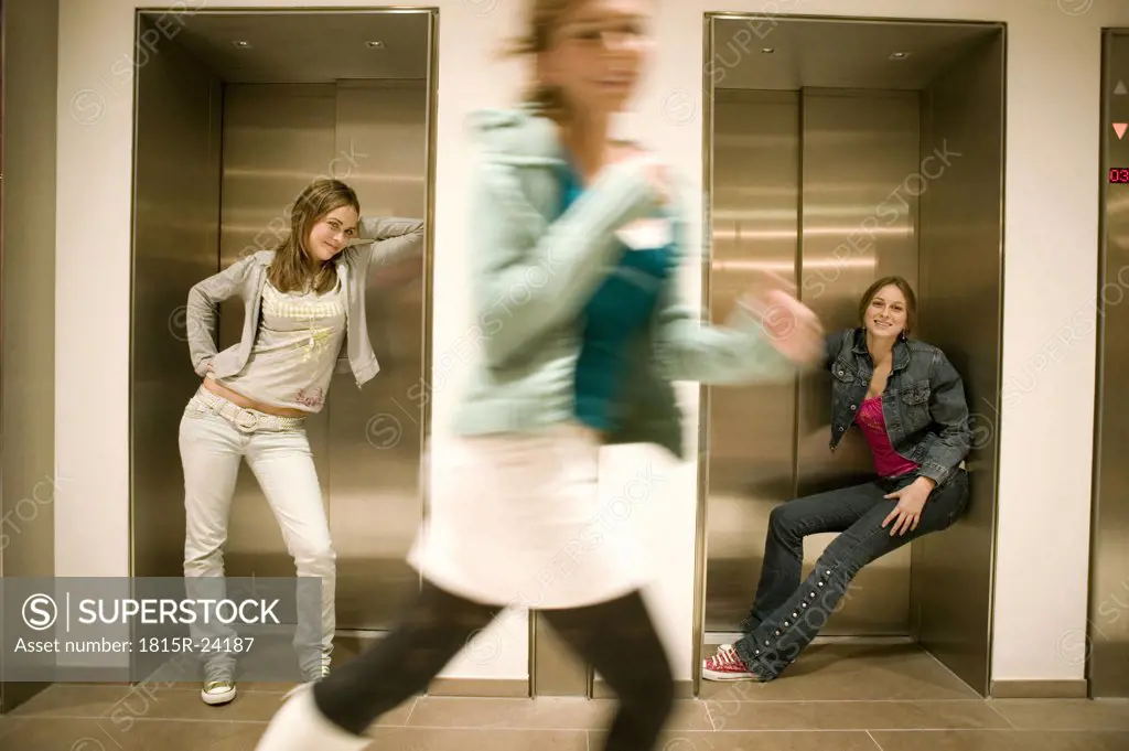 Two women leaning on lift door one woman running