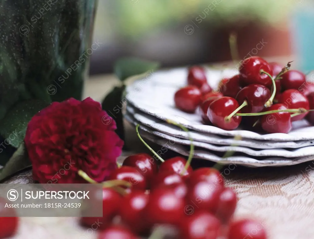 Cherries, peony and plates on table, close-up