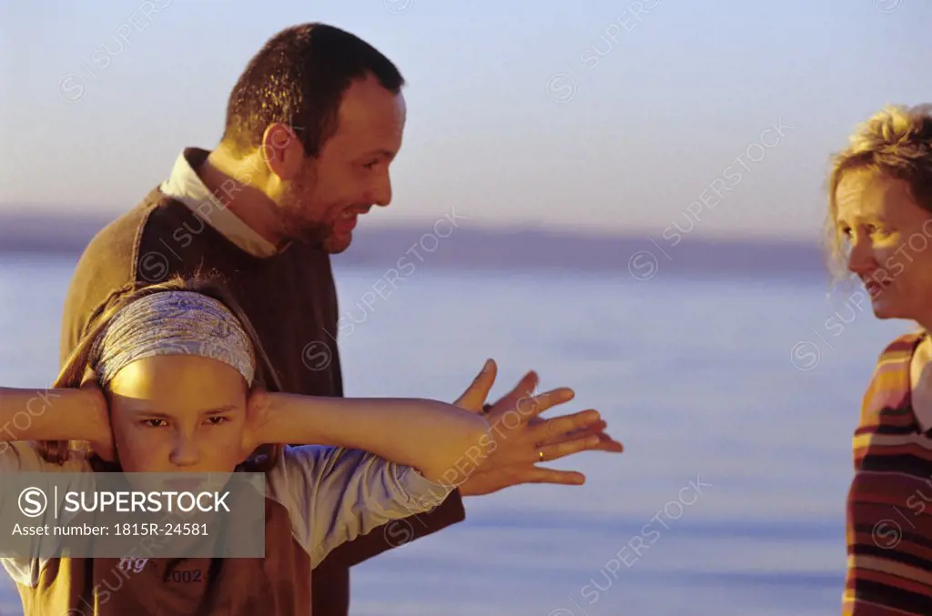 Parents in argument, girl (10-11) covering ears at beach