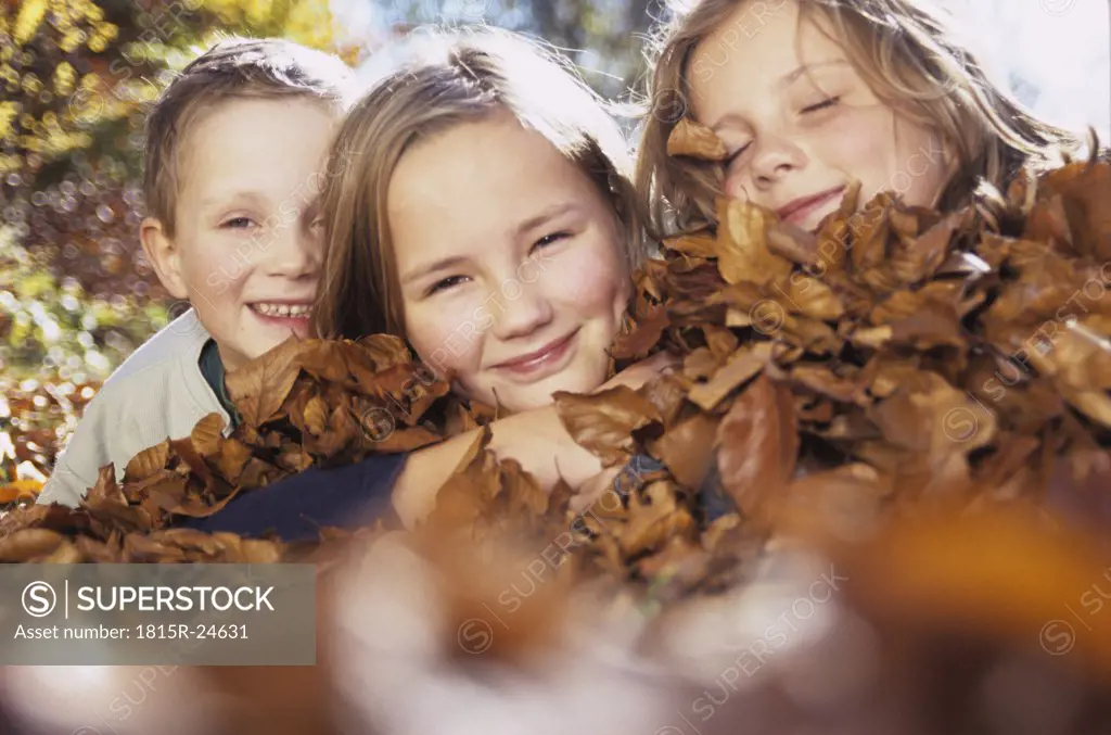 Children (4-13) lying on autumn leaves