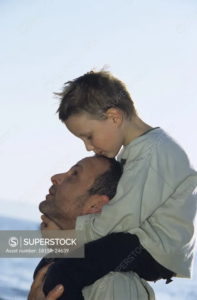 Father carrying son (4-7) on shoulders, close-up