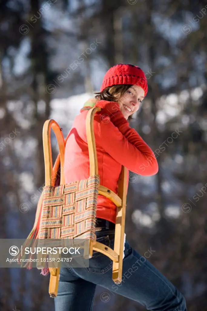 Woman holding sledge, smiling, portrait