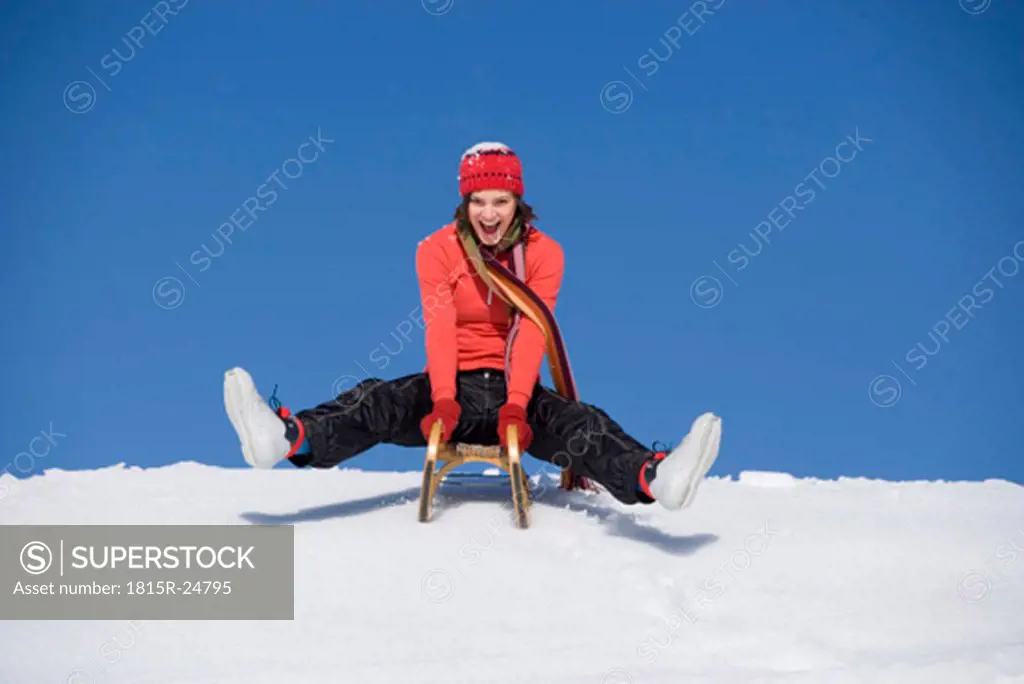 Woman riding on sledge, mouth open, low angle view