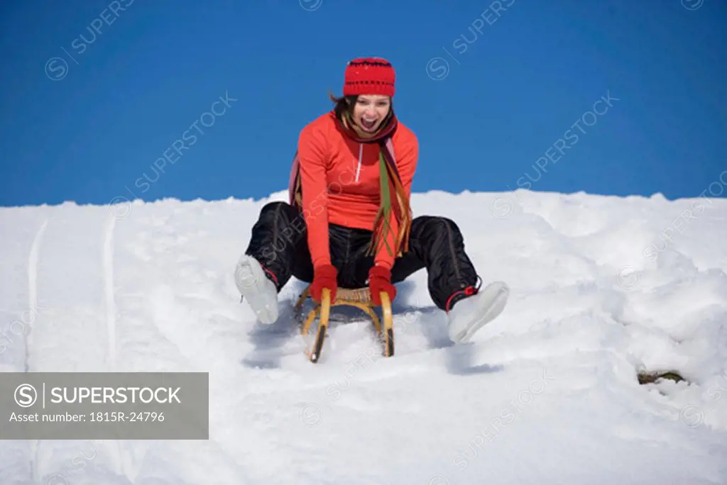 Woman riding on sledge, laughing, low angle view