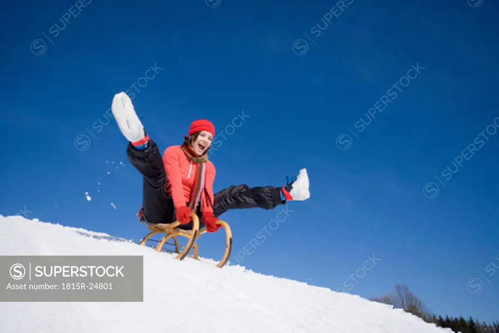 Woman on sledge, mouth open, low angle view