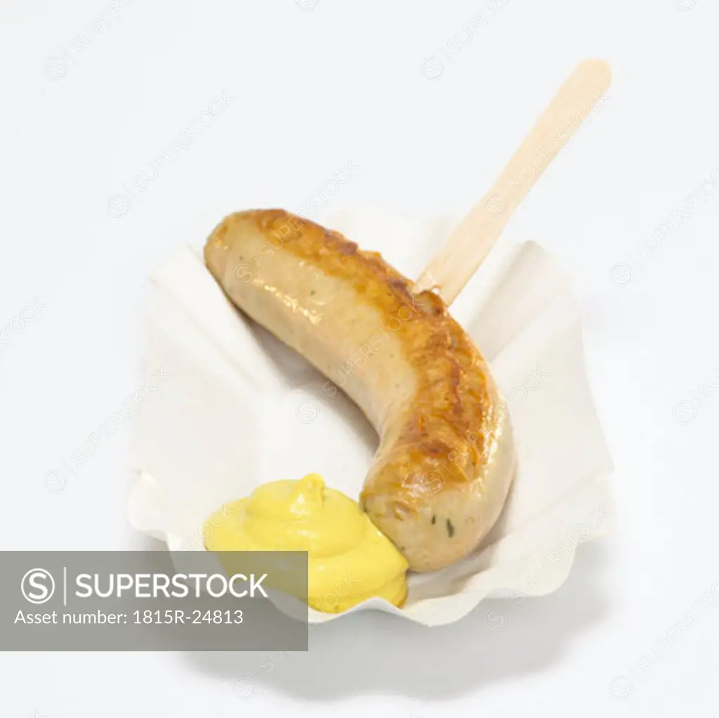 Fried sausage with mustard on paper plate