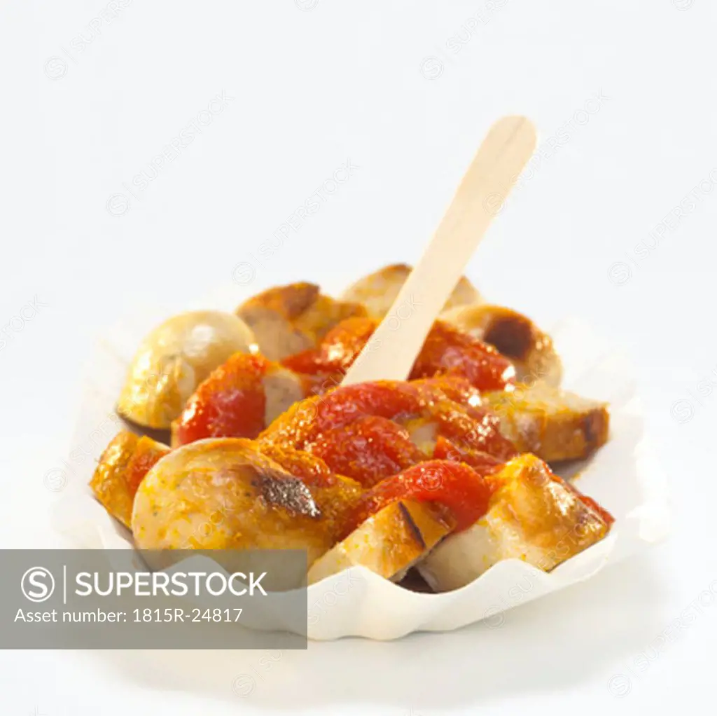 Sliced sausage with curry sauce on paper plate, Currywurst
