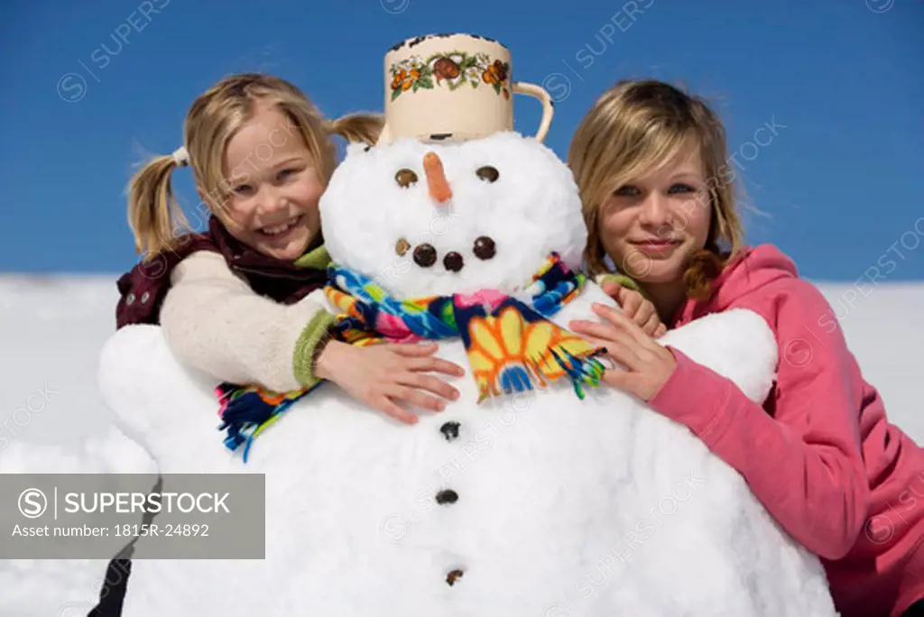 Girls embracing snowman