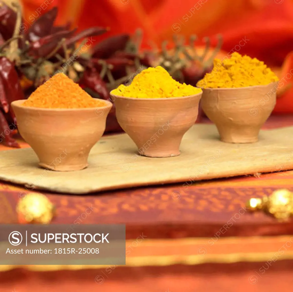 Curry, curcuma and chilli powder in bowls, close-up
