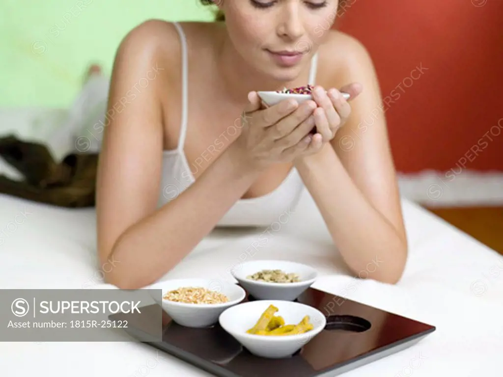 Woman lying on bed, holding spice in bowl