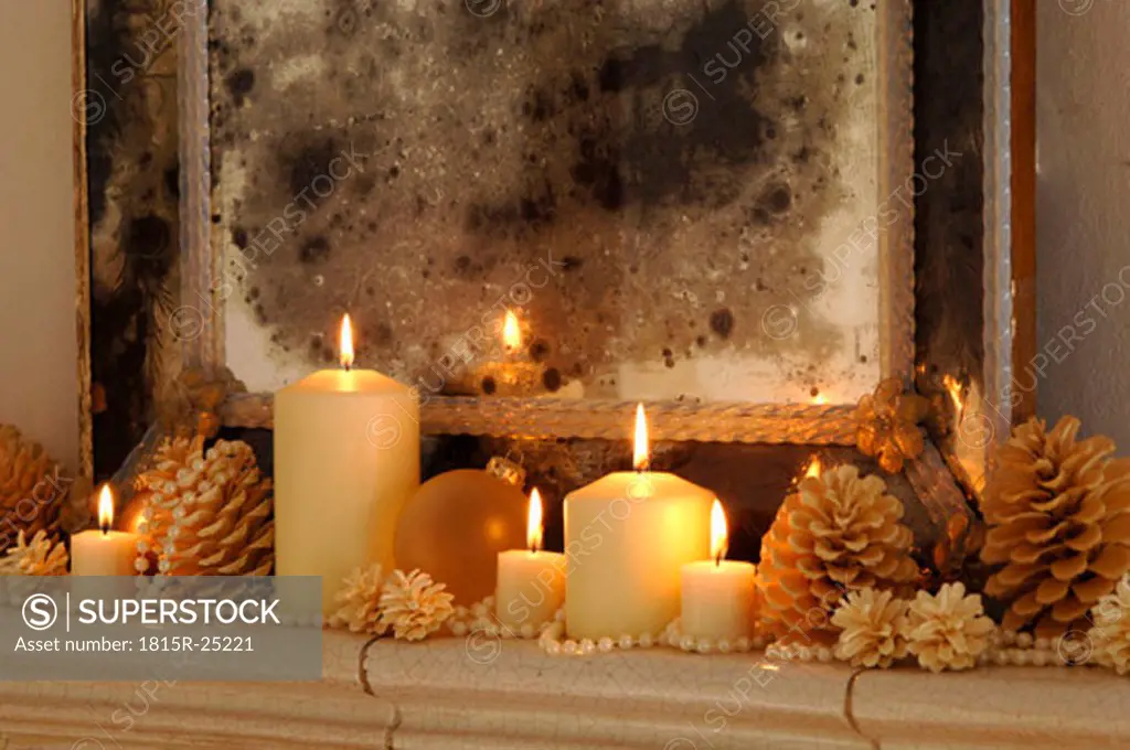 Burning candles with fir cones on shelf, close-up