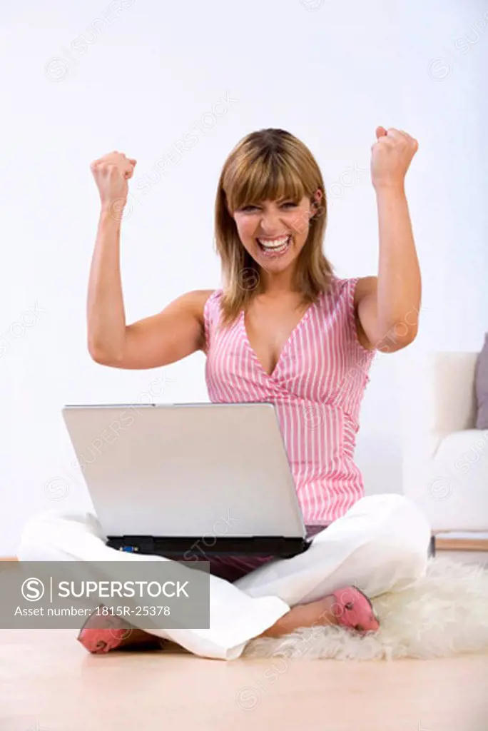 Young woman sitting on floor with laptop, portrait