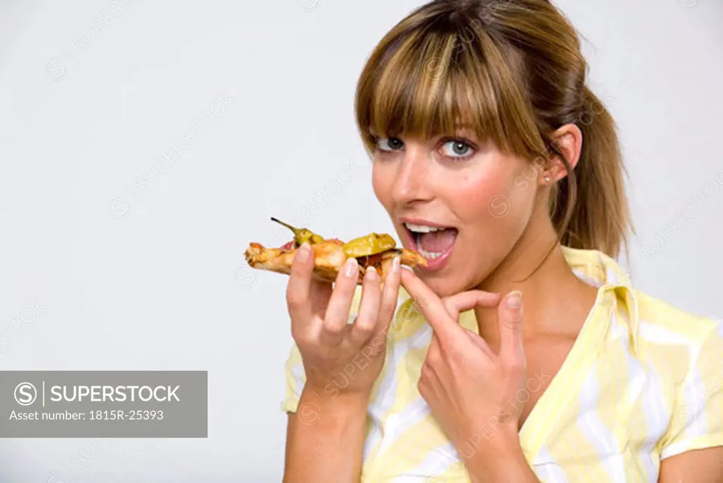 Young woman eating slice of pizza, close-up