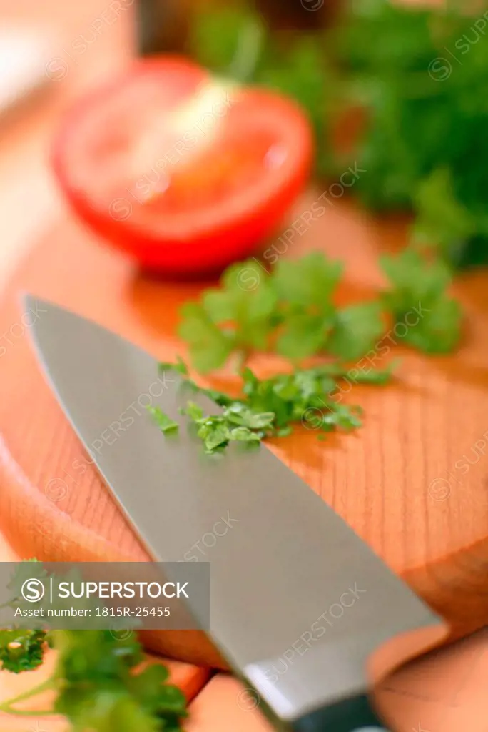 parsley, tomato and knife on chopping board