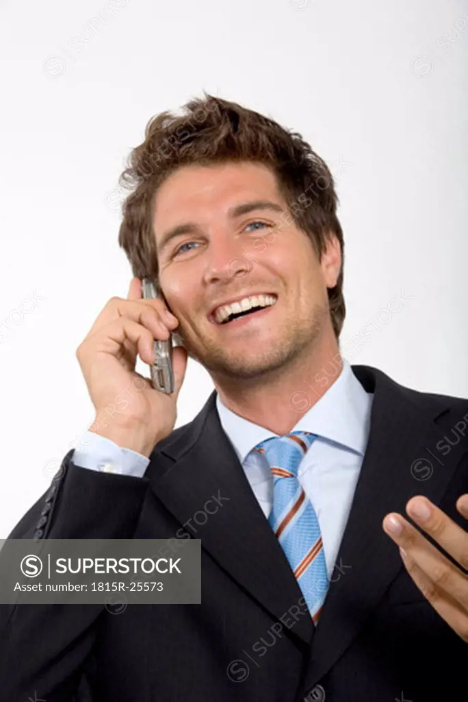 Young businessman using mobile phone, smiling, close-up
