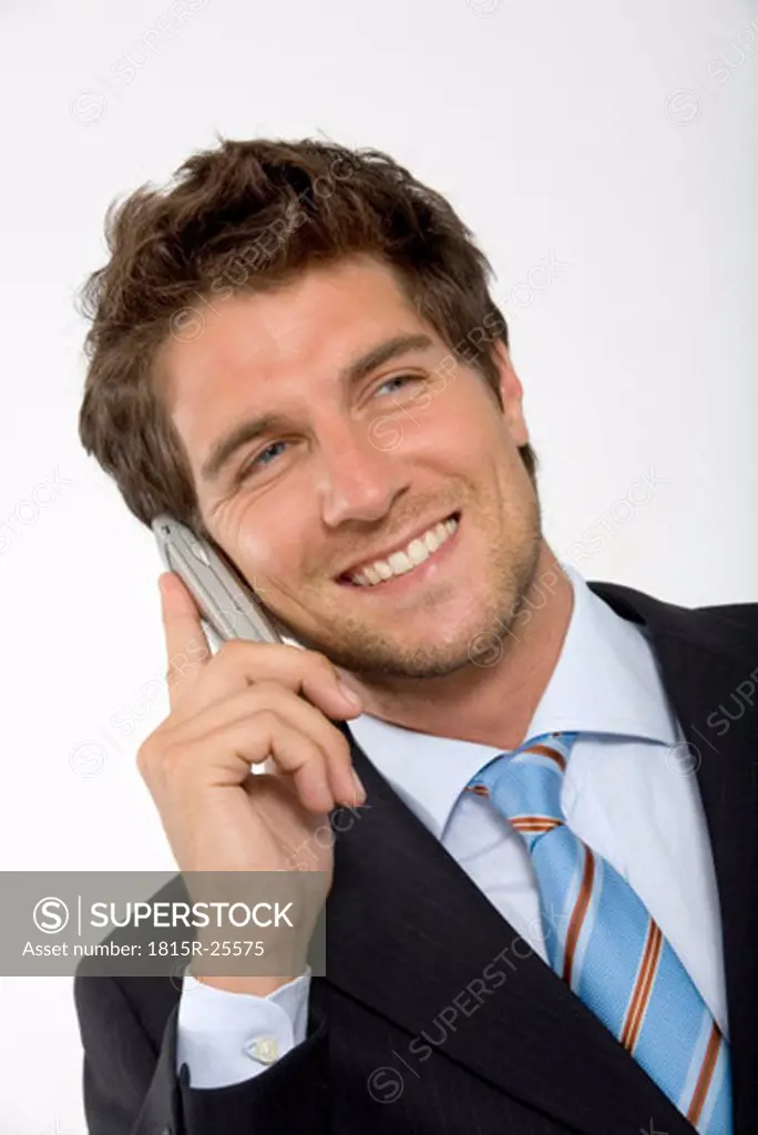 Young businessman using mobile phone, smiling, close-up