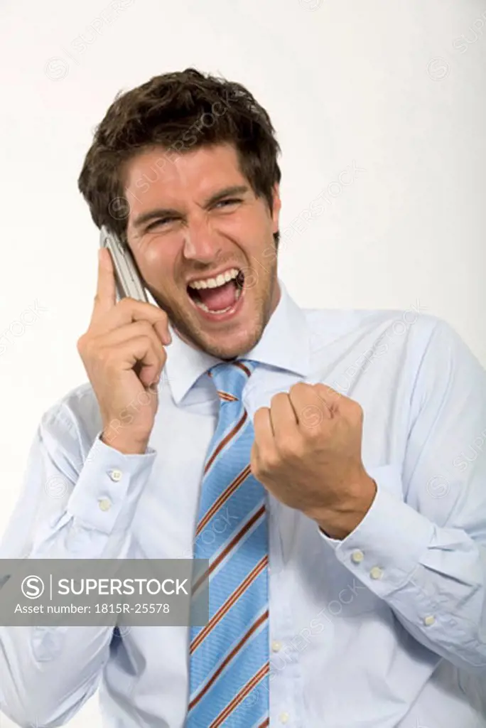 Young businessman using mobile phone, shouting, close-up
