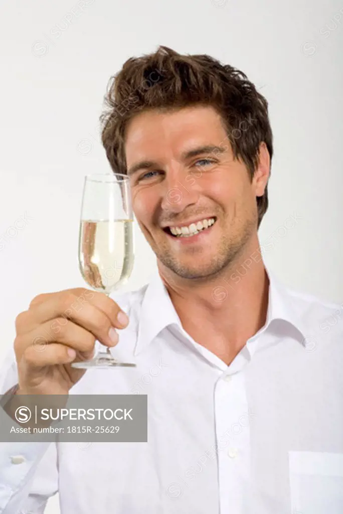 Young man holding glass of champagne, close-up, portrait