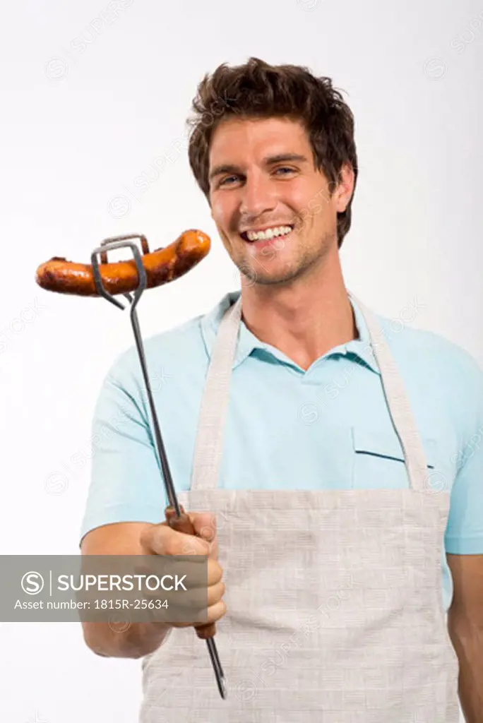 Young man with grilled sausage