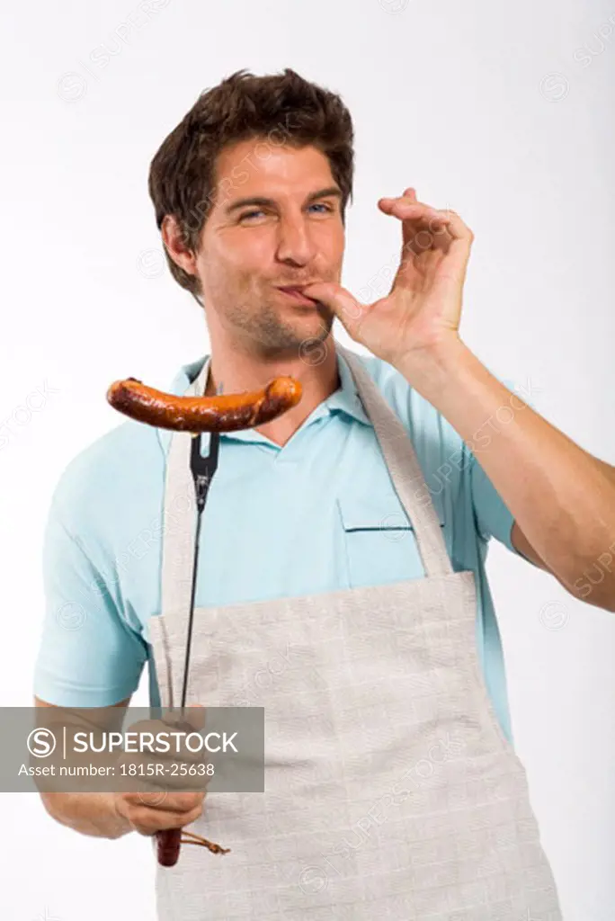 Young man with grilled sausage on fork, portrait