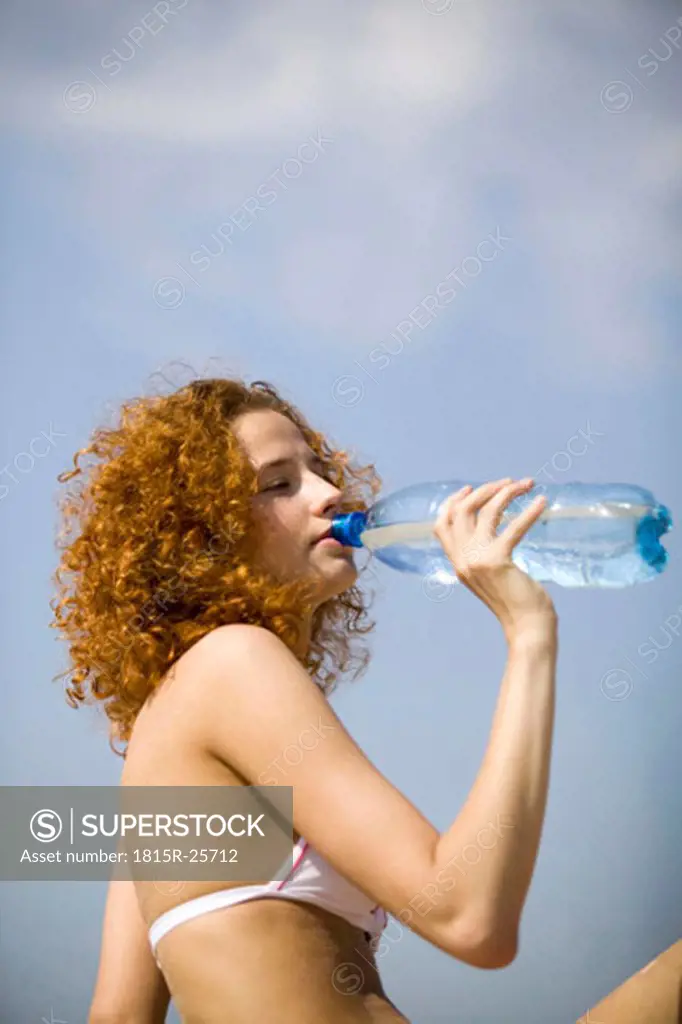 Young woman drinking water from bottle, close-up